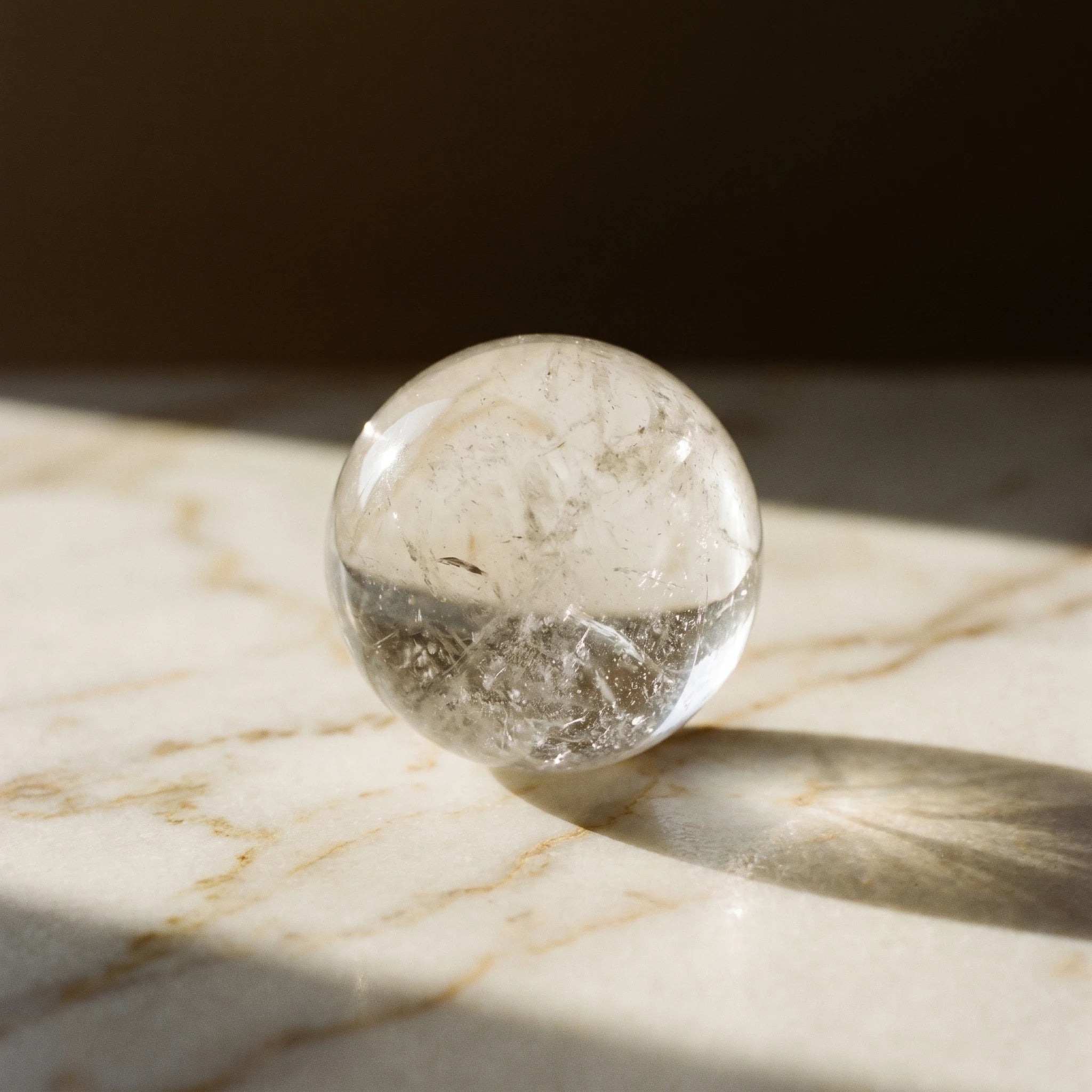 La Boule de Cristal — Sphère de quartz transparent 28–32 mm + socle bois — détail matière · AURÆN Pierres d'Âme